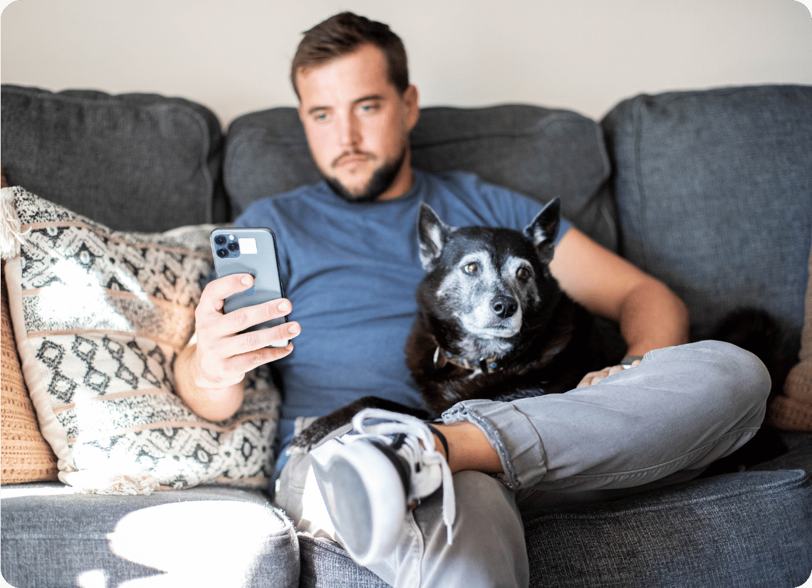 Pet parent on their phone while sitting with their dog