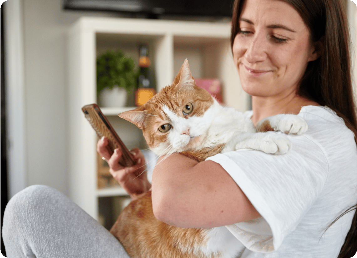 Pet parent on their phone while holding their cat
